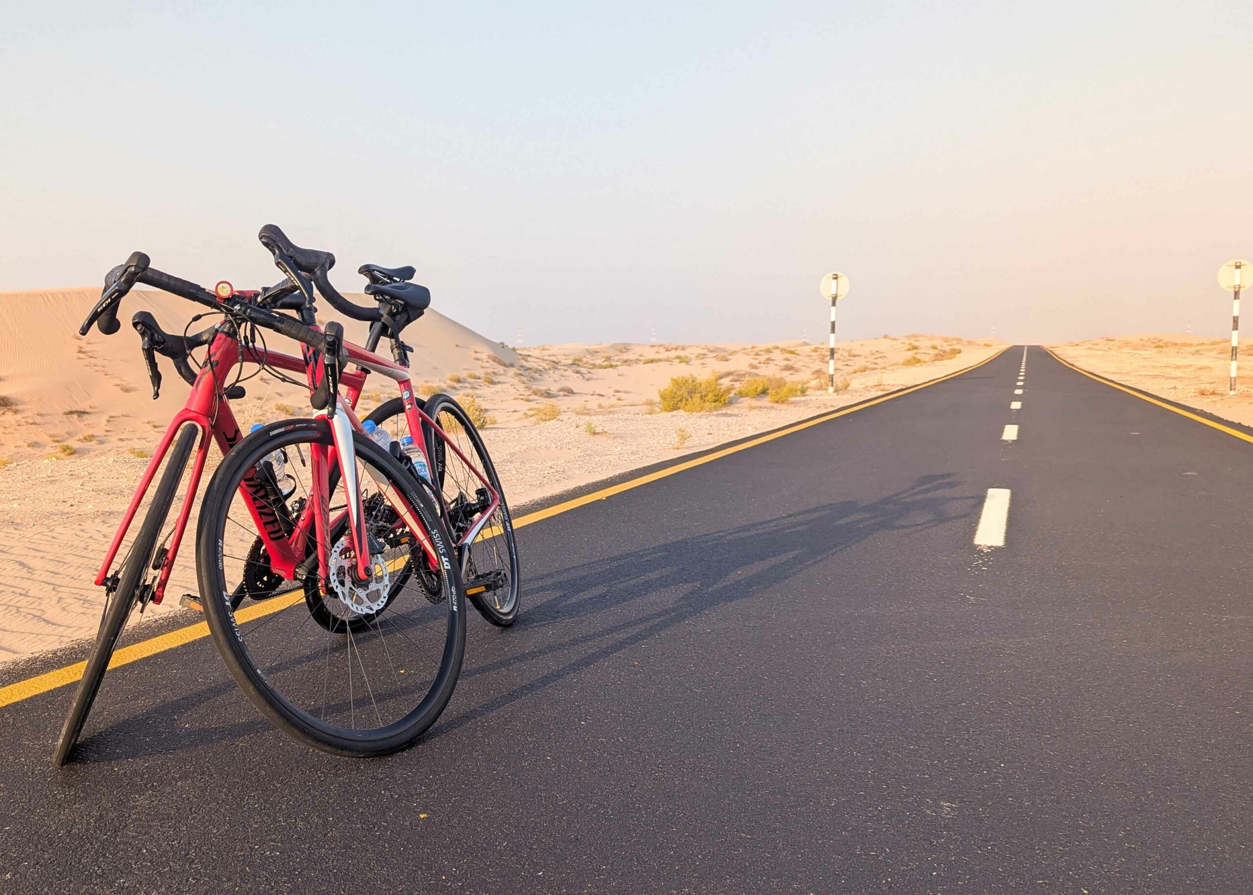 lesvoyagesdapogee-abudhabi-desert-Al-Wathba-michael-paikert Deux vélos de route rouges arrêtés sur la piste cyclable d’Al Wathba, au cœur du désert d’Abu Dhabi