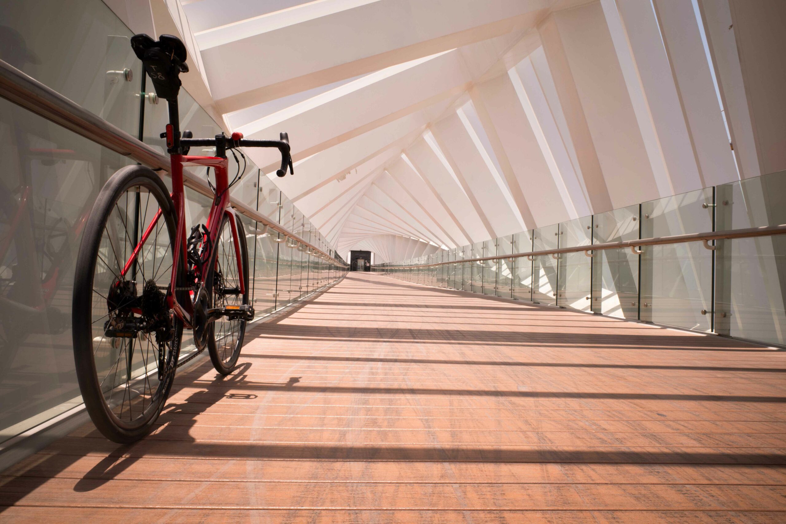 lesvoyagesdapogee-dubaï-businessbay-cyclepath-watercanal-footbridge-michael-paikert Vélo de route posé sur la passerelle cyclable du Dubai Water Canal à Business Bay, dans une architecture moderne et lumineuse